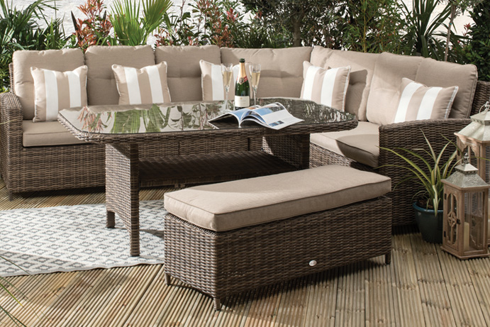 Rattan corner sofa on decking adorned with cushions in a beige colour.