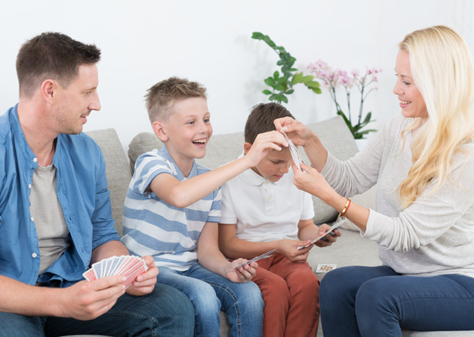 Happy young family playing card game on living room sofa at home