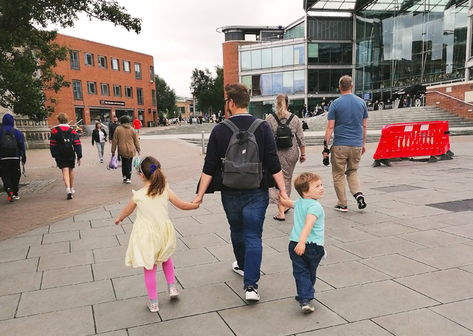 Father holding hands with two children walking through the city during summer holidays