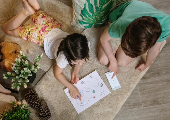 Children looking at a treasure map and compass on a smartphone