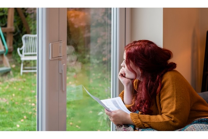 Young woman with red hair watching birds from her back door