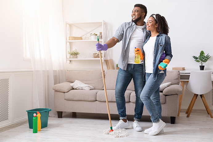 couple standing with cleaning products in a very tidy living room looking accomplished after spring cleaning