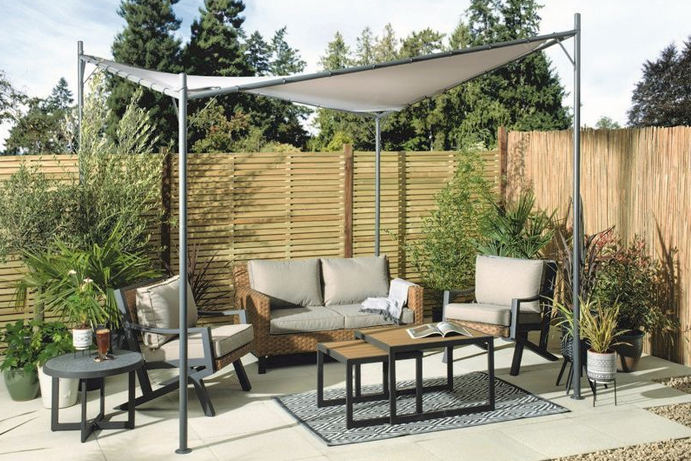 Minimalist curved gazebo covering a rattan sofa set surrounded by large outdoor plants
