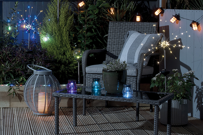 Garden armchair and coffee table on decking surrounded by outdoor solar lights