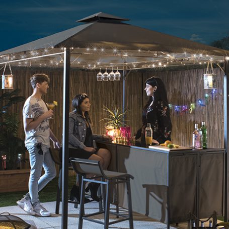 Three young adults enjoying drinks under a gazebo in the evening