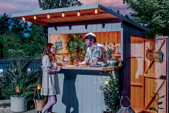 A man and woman enjoying drinks at the bar shed in the evening time