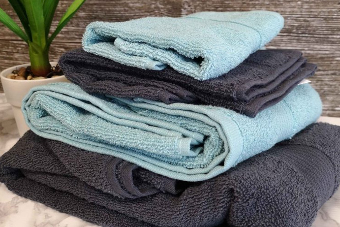 light blue and black towels folded and piled neatly on a bathroom side