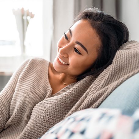 Lady smiling on a sofa with a cosy jumper on