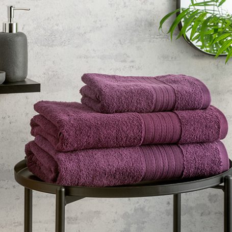Purple towels folded on a black metal table in a bathroom