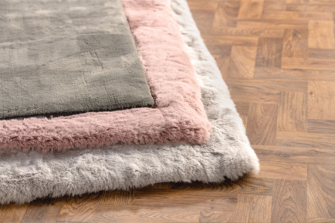 soft faux fur rugs in pink, light grey and darker grey on a wooden floor