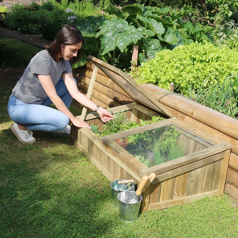 an image of a cold frame greenhouse with a woman tending to the plants